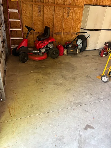Cleared garage floor with lawn equipment along the wall
